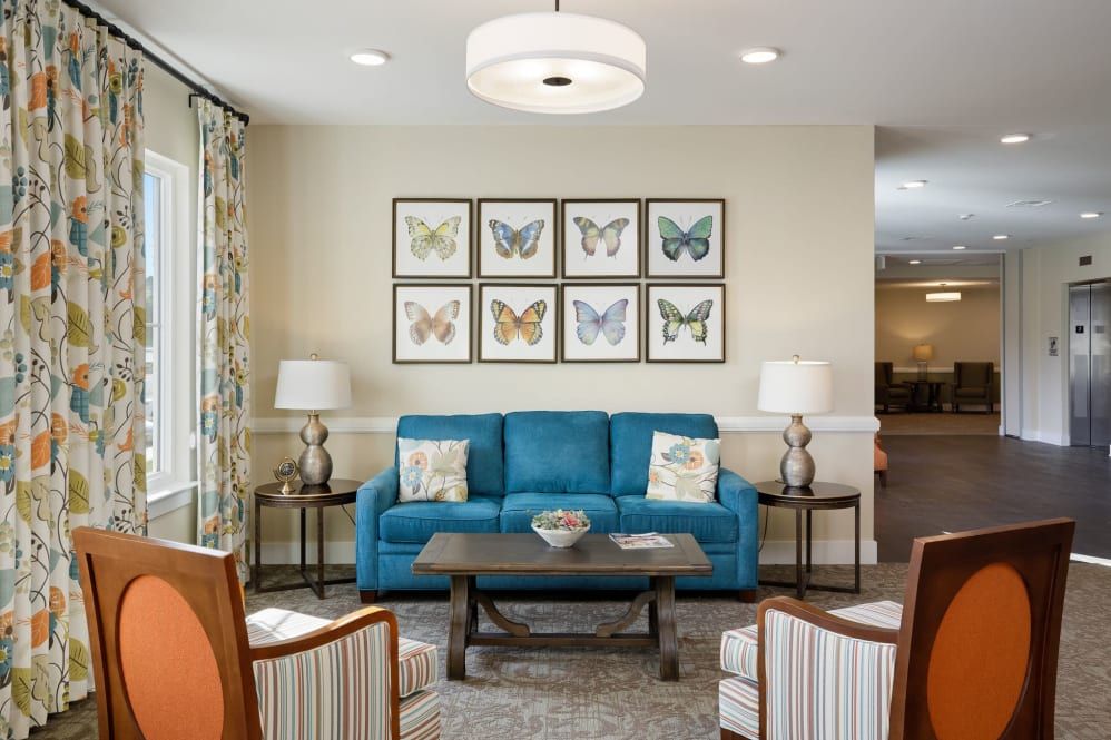 A cozy living room featuring a blue sofa, butterfly wall art, and elegant lighting.