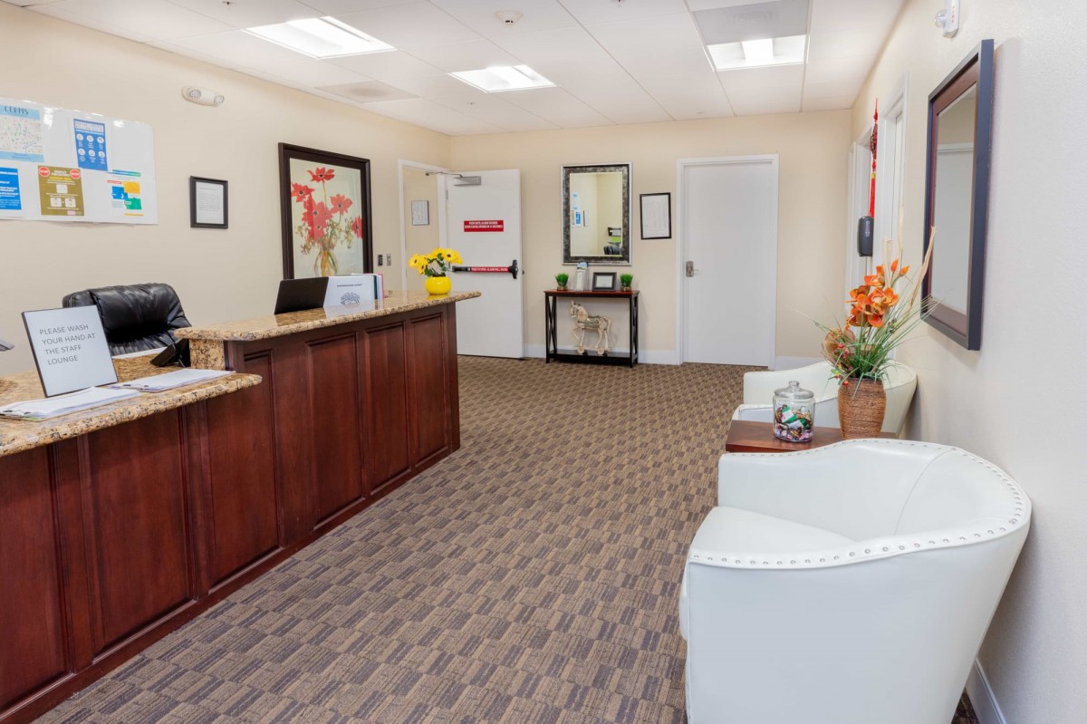 A neatly arranged office reception area with a desk, chairs, and decorative artwork.