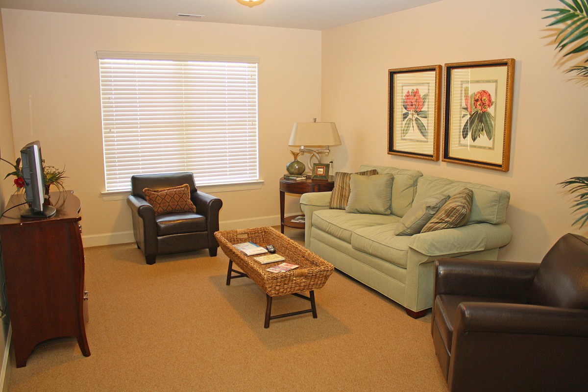 A cozy living room with a sofa, armchair, coffee table, and wall artwork.