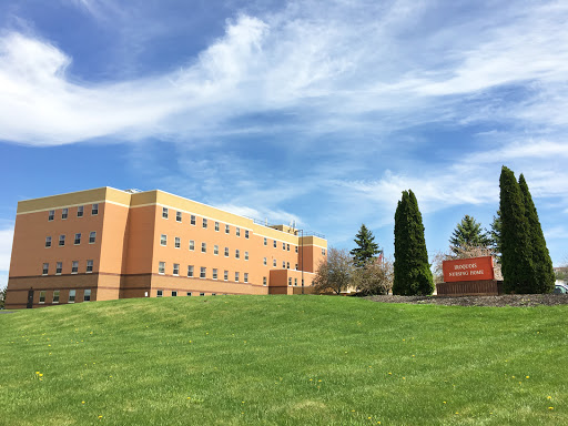 A sunny day showcasing a multi-story educational building surrounded by lush green grass and a clear blue sky.