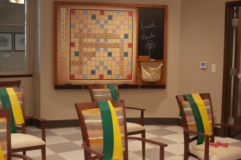 A game room featuring a large Scrabble board on the wall with chairs arranged nearby.