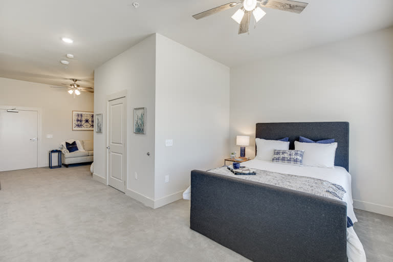 A modern bedroom interior featuring a large bed with a sleek headboard, bedside lamps, and a ceiling fan, creating a comfortable and stylish living space.