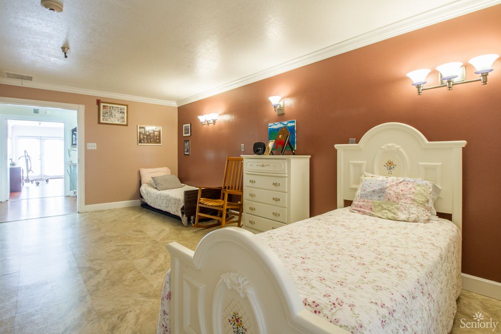 A cozy bedroom featuring a single bed, dresser, chair, and decorative wall art.