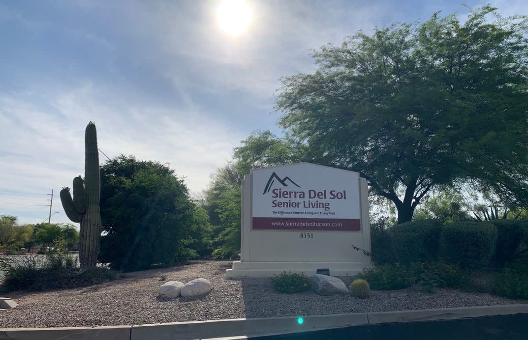 A business sign for Sierra Del Sol Senior Living under a sunny sky with surrounding trees.