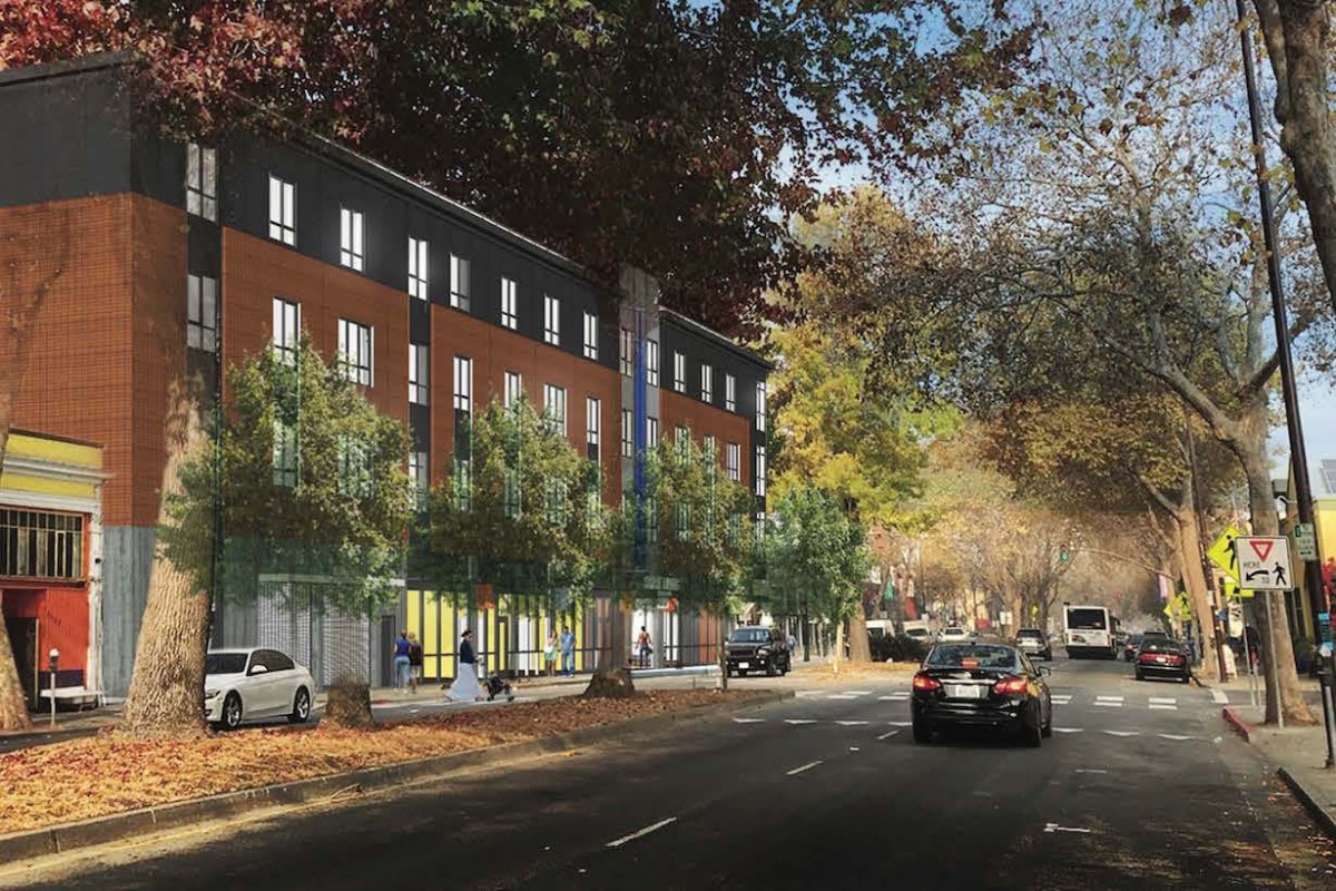 A view of a city street with cars driving by a modern building lined with trees.