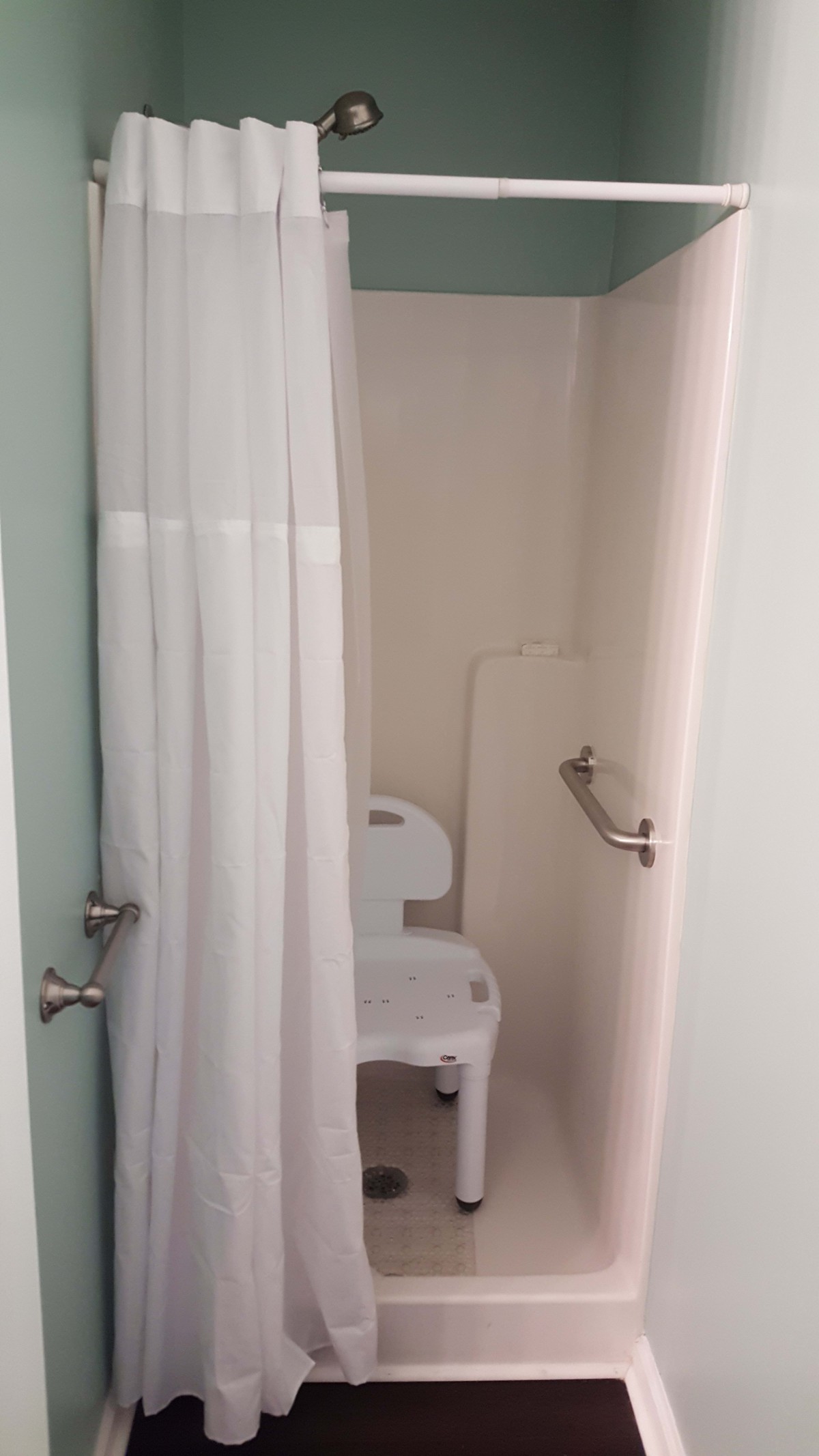 An accessible shower with a chair and safety grab bar.