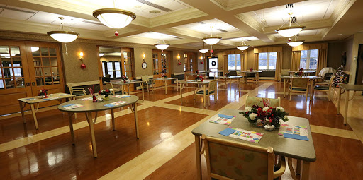 A spacious interior room featuring several tables, warm lighting, and a polished wooden floor, suitable for gatherings or events.