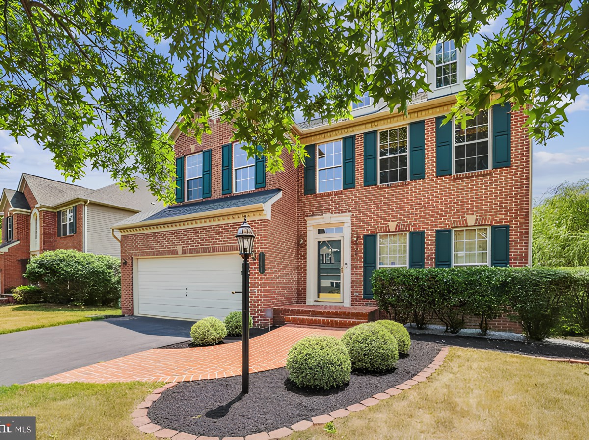 A suburban brick house with a well-maintained front yard and attached garage.