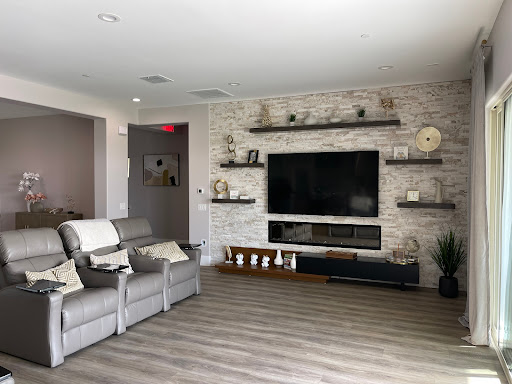 A modern living room featuring a cozy seating area, wall-mounted television, and stylish shelves.
