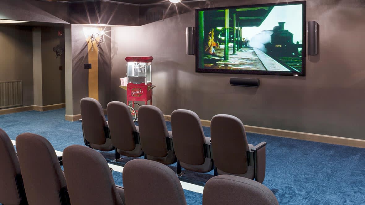 A cozy home theater setup with comfortable seating, a large screen, and a popcorn machine for an immersive movie experience.