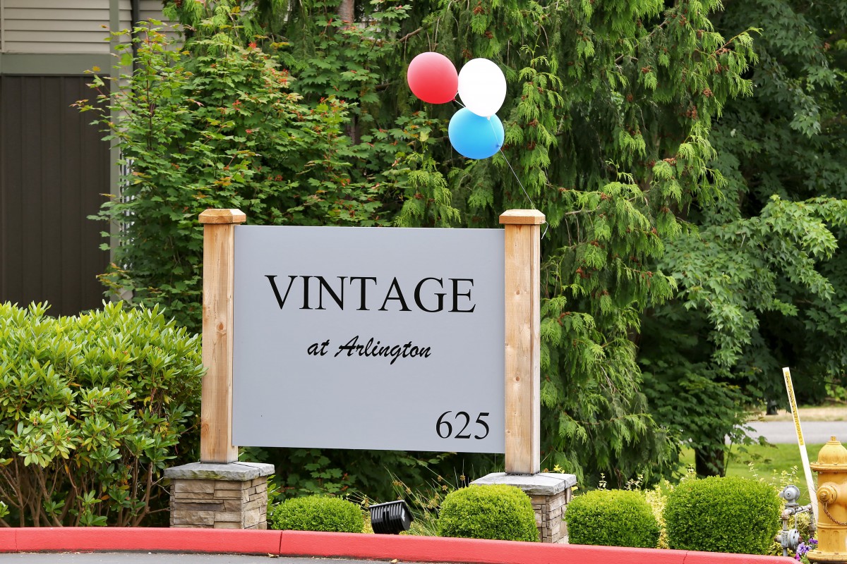 A sign for Vintage at Arlington with red, white, and blue balloons attached.