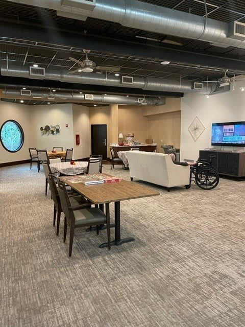 A modern office workspace featuring conference tables, chairs, a television, and stylish decor.