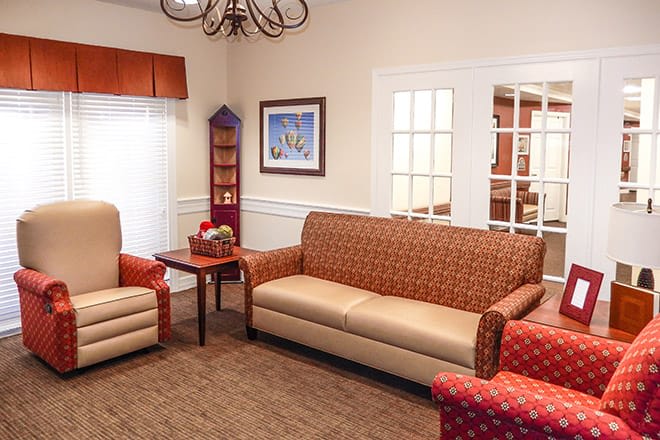 A cozy living room with a sofa, armchairs, and a coffee table, decorated with artwork on the wall.
