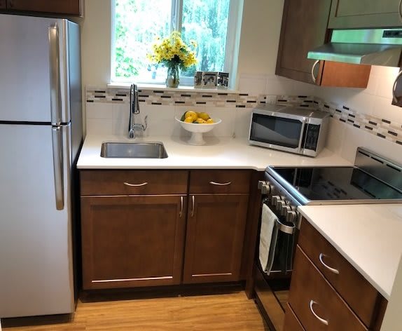 A modern kitchen with stainless steel appliances, wooden cabinets, and a bright window.